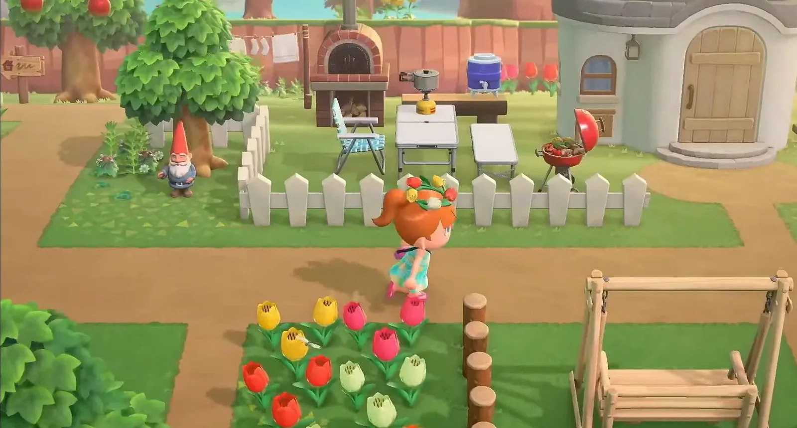 Un habitant d'Animal Crossing: New Horizons devant son parterre de tulipes, barrière blanche et jardin aménagé